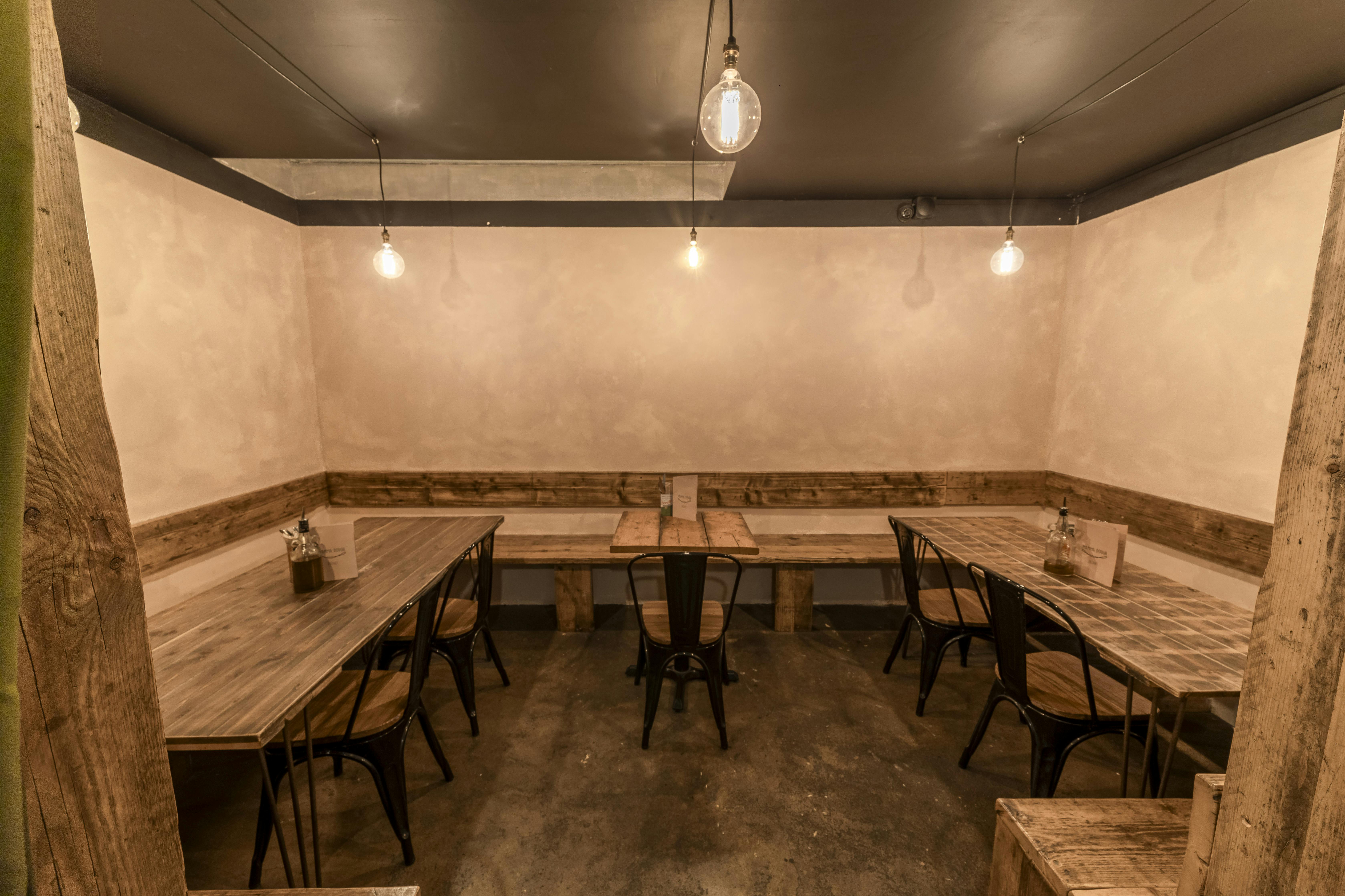 Minimalist meeting space at The Pizza Parlour, rustic tables for intimate gatherings.