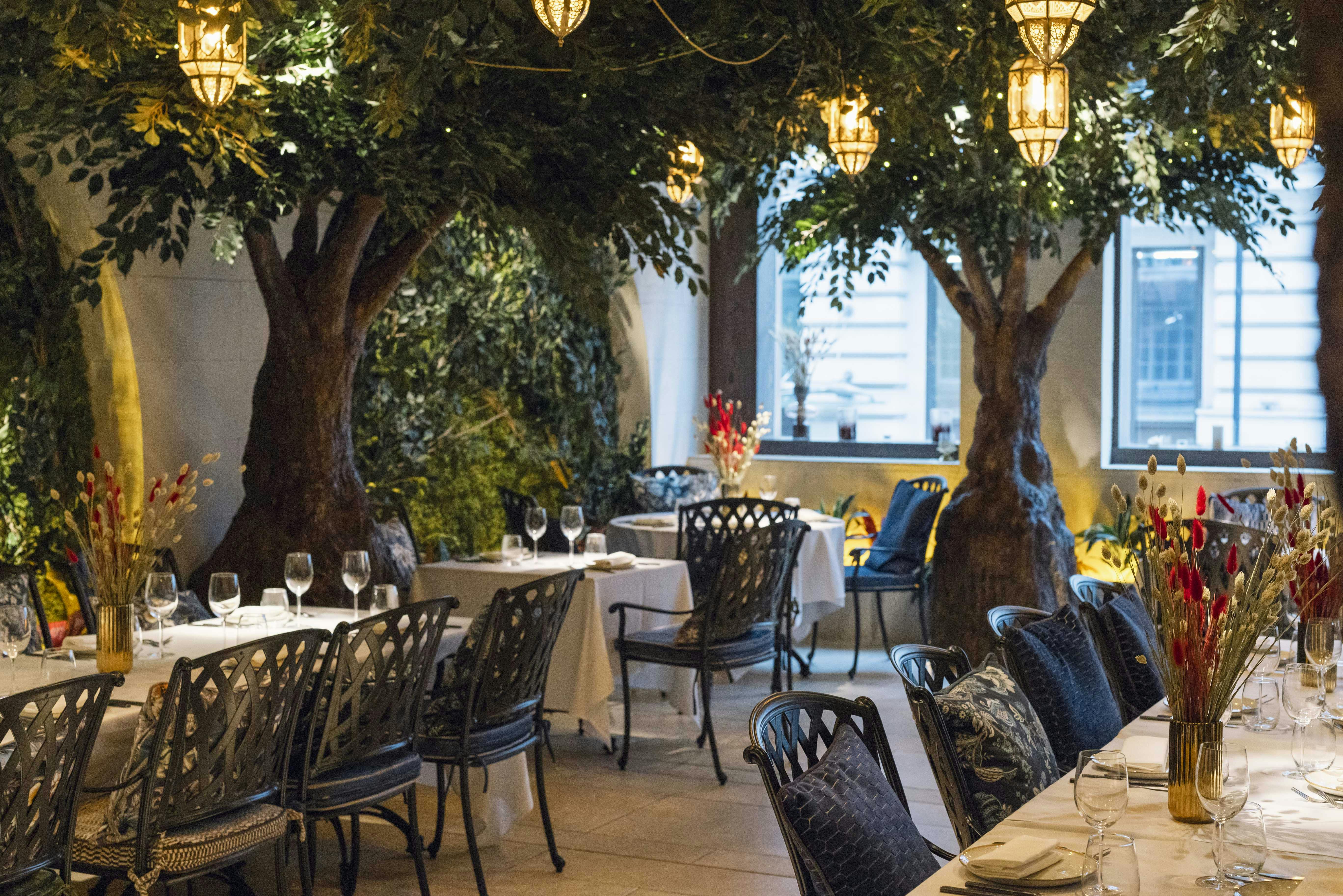 "Elegant dining space at Jeru Garden with faux trees, ideal for private events."