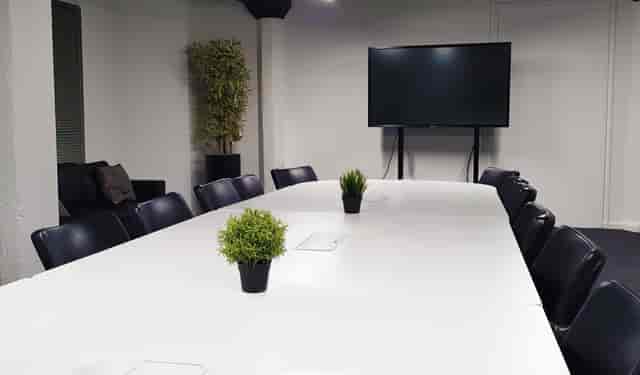 Modern Glasgow training room with white table, black chairs, ideal for meetings and presentations.