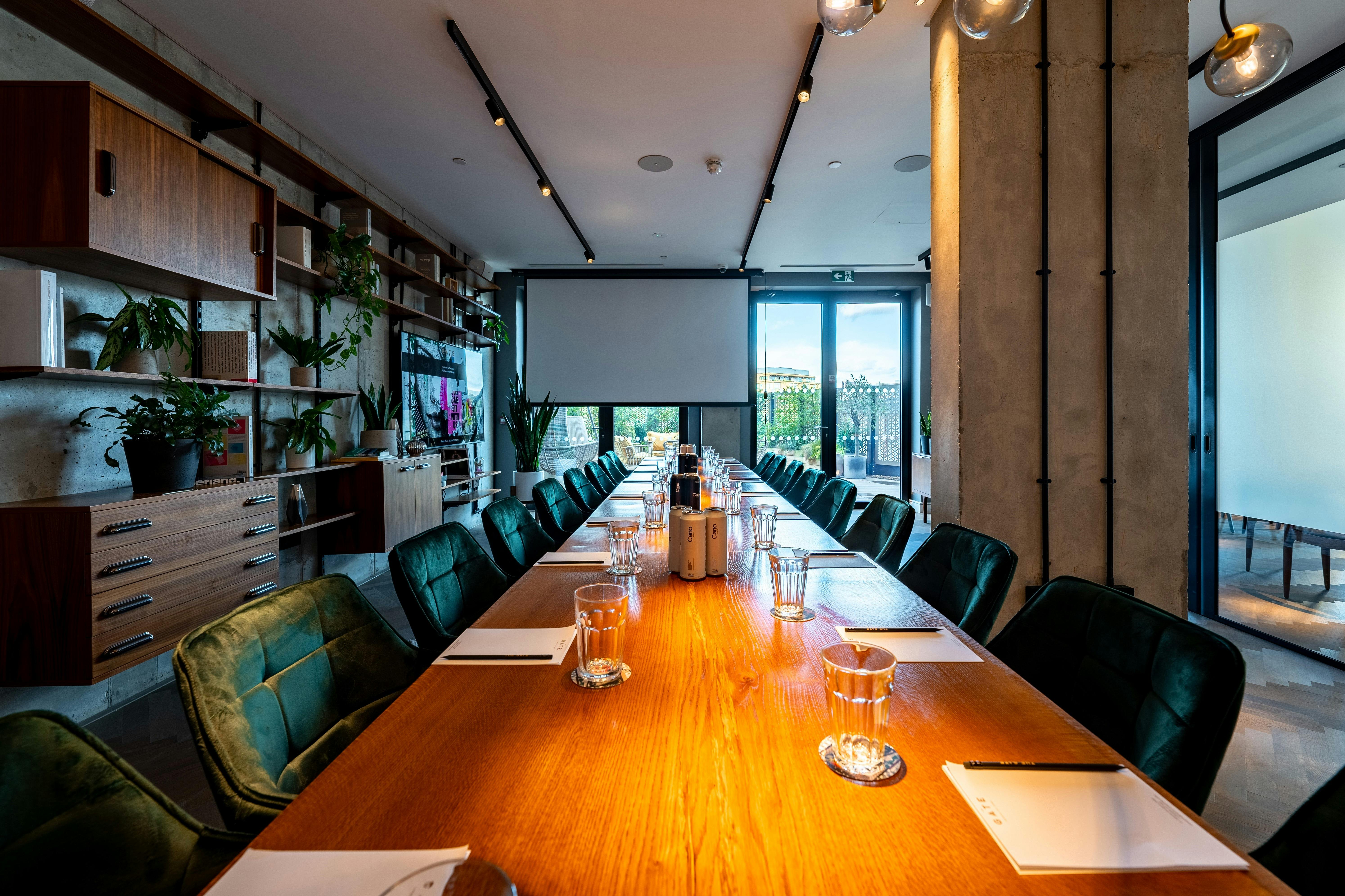 Modern meeting room with long wooden table at The Gate Aparthotel, ideal for events.