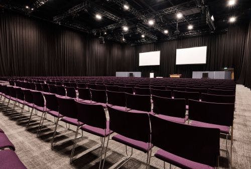 ICC Belfast conference venue with empty chairs and stage, perfect for presentations and workshops.