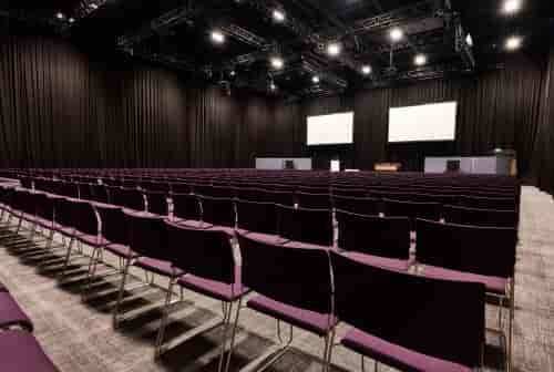 Spacious ICC Belfast event space set for a conference with empty chairs and large screens.