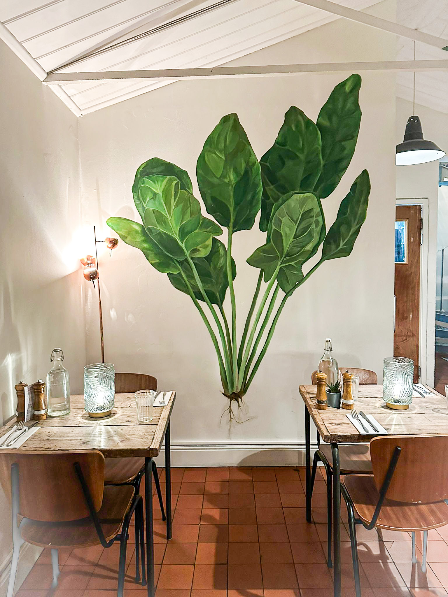 Stylish dining venue in Spinach East Dulwich with vibrant leaf mural, perfect for events. - Banner