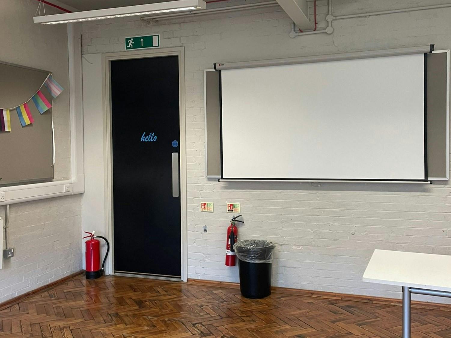 Rehearsal Room 2 with projector screen, ideal for presentations and events.