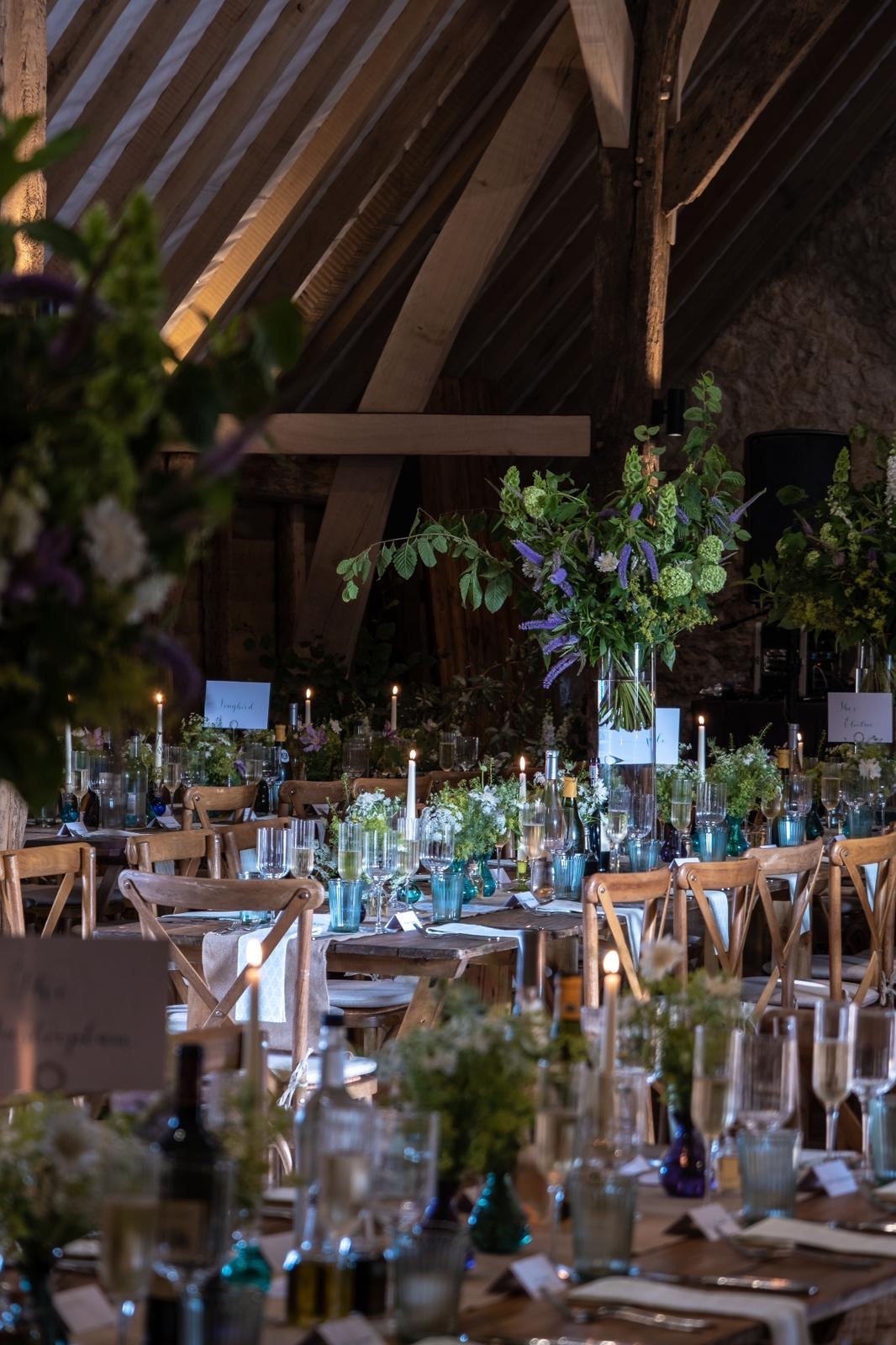 Elegant wooden tables with floral centerpieces in Ruffynes Barn for weddings and events. - Banner