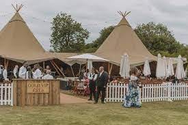 Elegant teepee tents for upscale outdoor events in Raw Tipis, featuring white umbrellas.