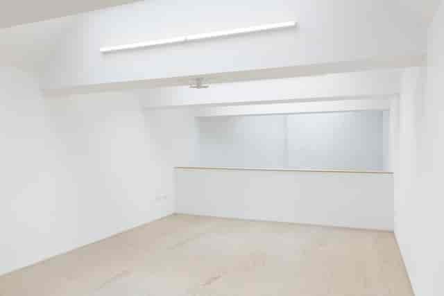 Minimalist event space with white walls and wooden floor, ideal for meetings and workshops.