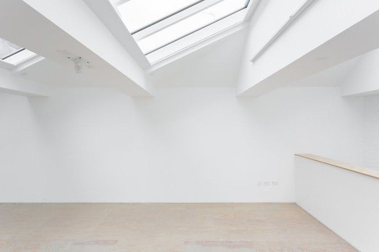 Bright minimalist event space with skylights, perfect for meetings and workshops.