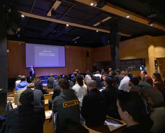Engaged audience at a modern presentation in Hackney Wick venue with tech-enabled setup.