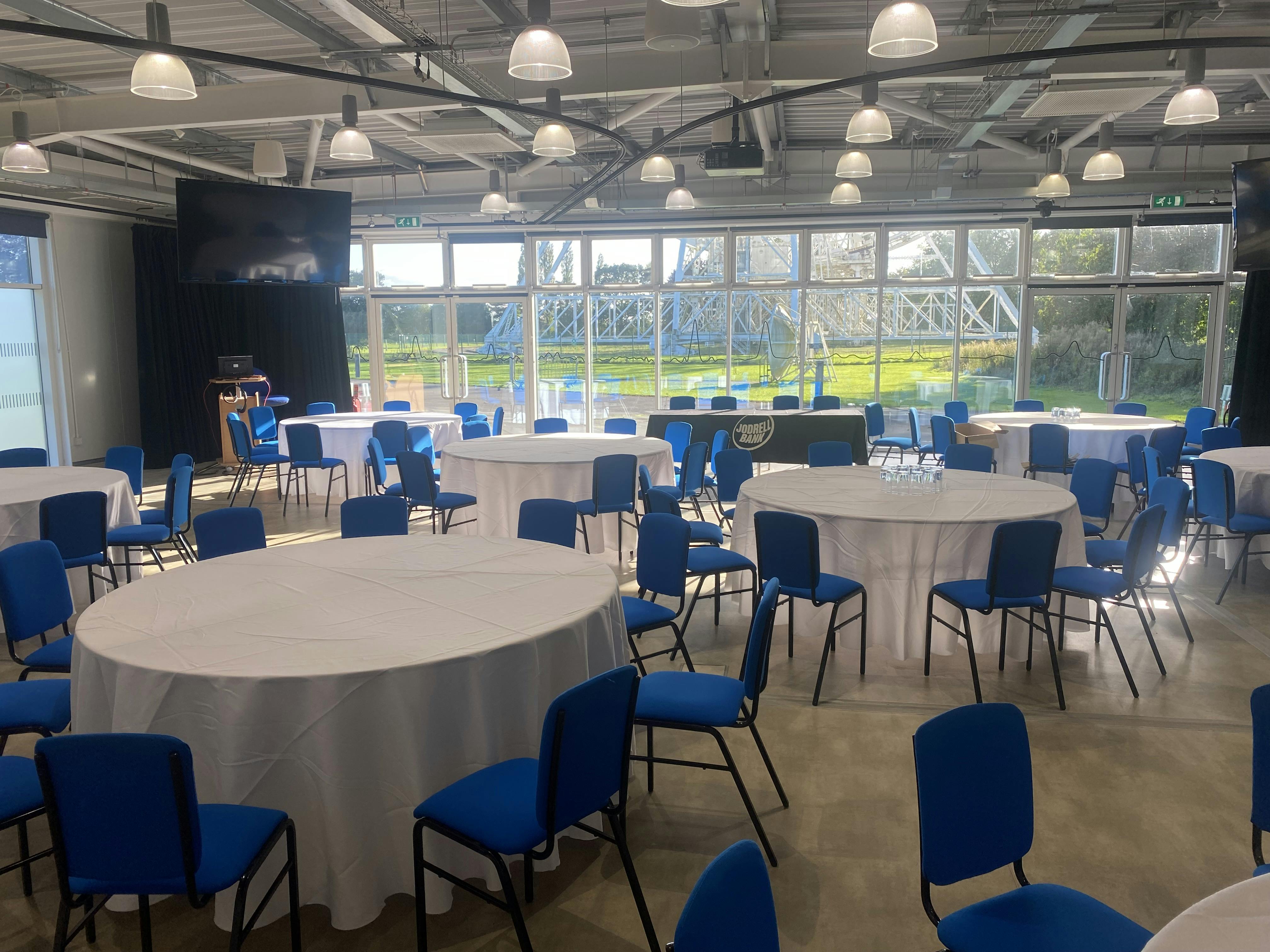 Wolfson Auditorium setup for meetings with round tables and blue chairs, ideal for events.