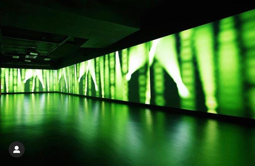 Sleek event space with immersive green projections for innovative presentations and networking.