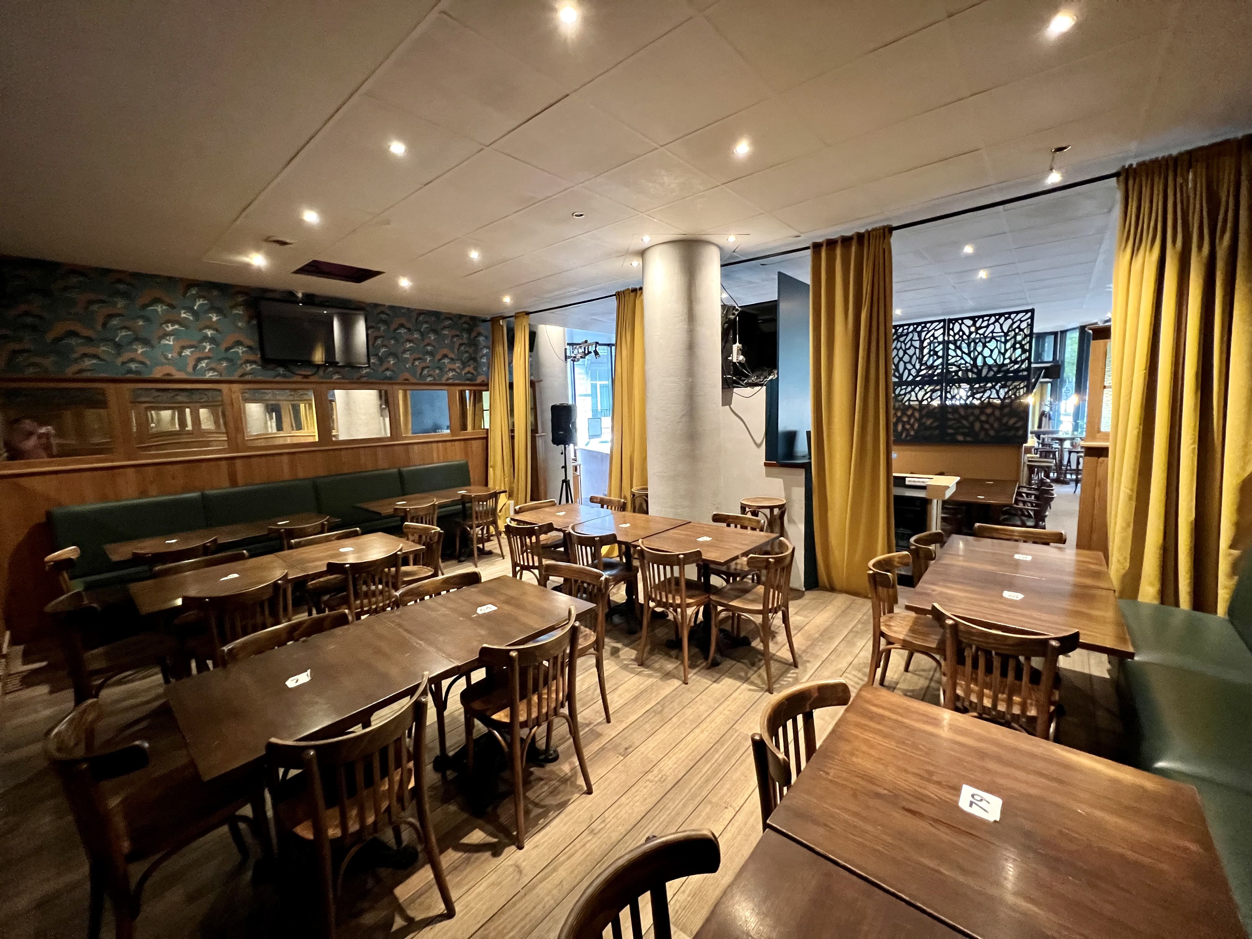 Cinquantenaire Social Club event space with wooden tables, ideal for meetings and gatherings.