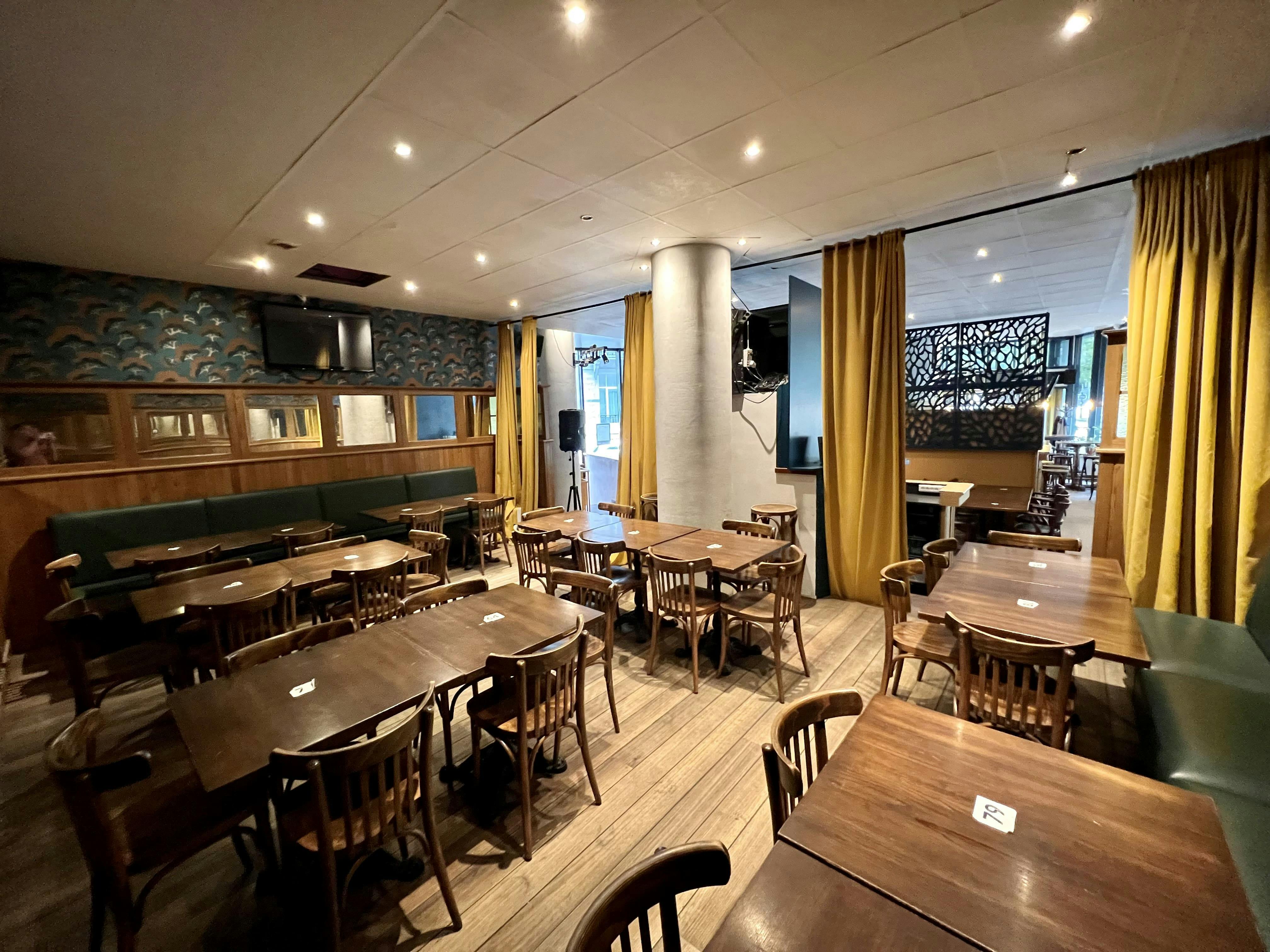 Cinquantenaire Social Club event space with wooden tables, ideal for meetings and gatherings.