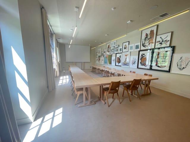 Meeting room l’Aquarelle with wooden table, ideal for workshops and strategic meetings.