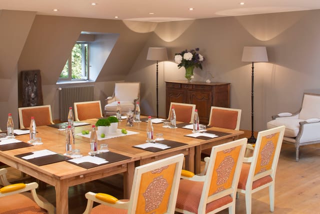 Intimate meeting room at La Ferme saint Siméon with wooden table, ideal for workshops.