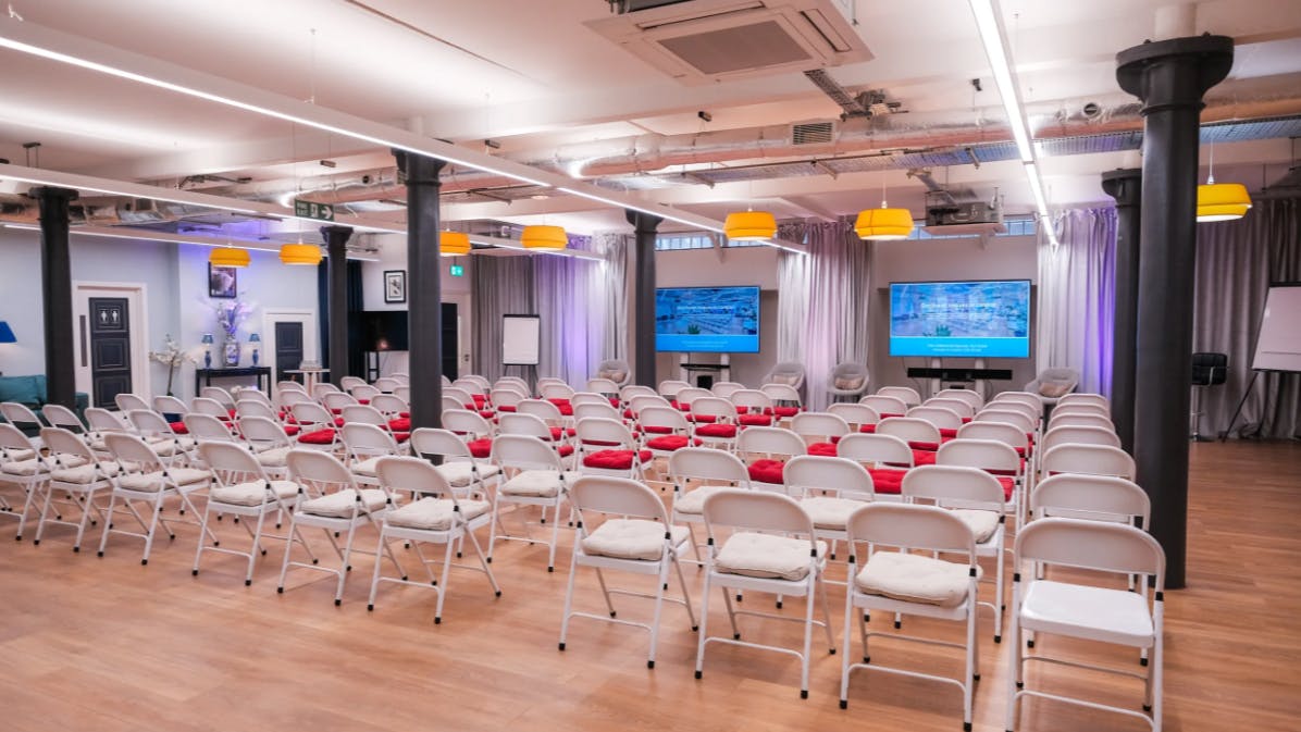 La Galeria event space with white chairs and dual screens for presentations and workshops.