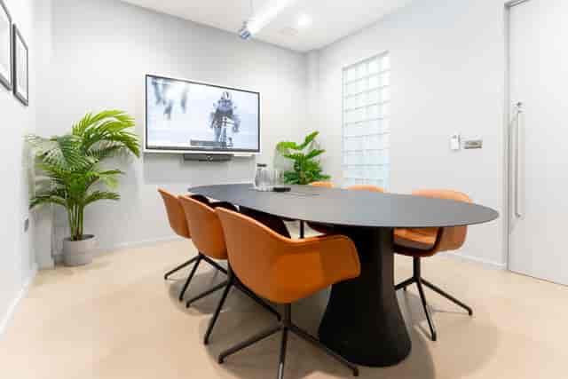 Modern meeting room with black table, orange chairs, ideal for collaboration and presentations.