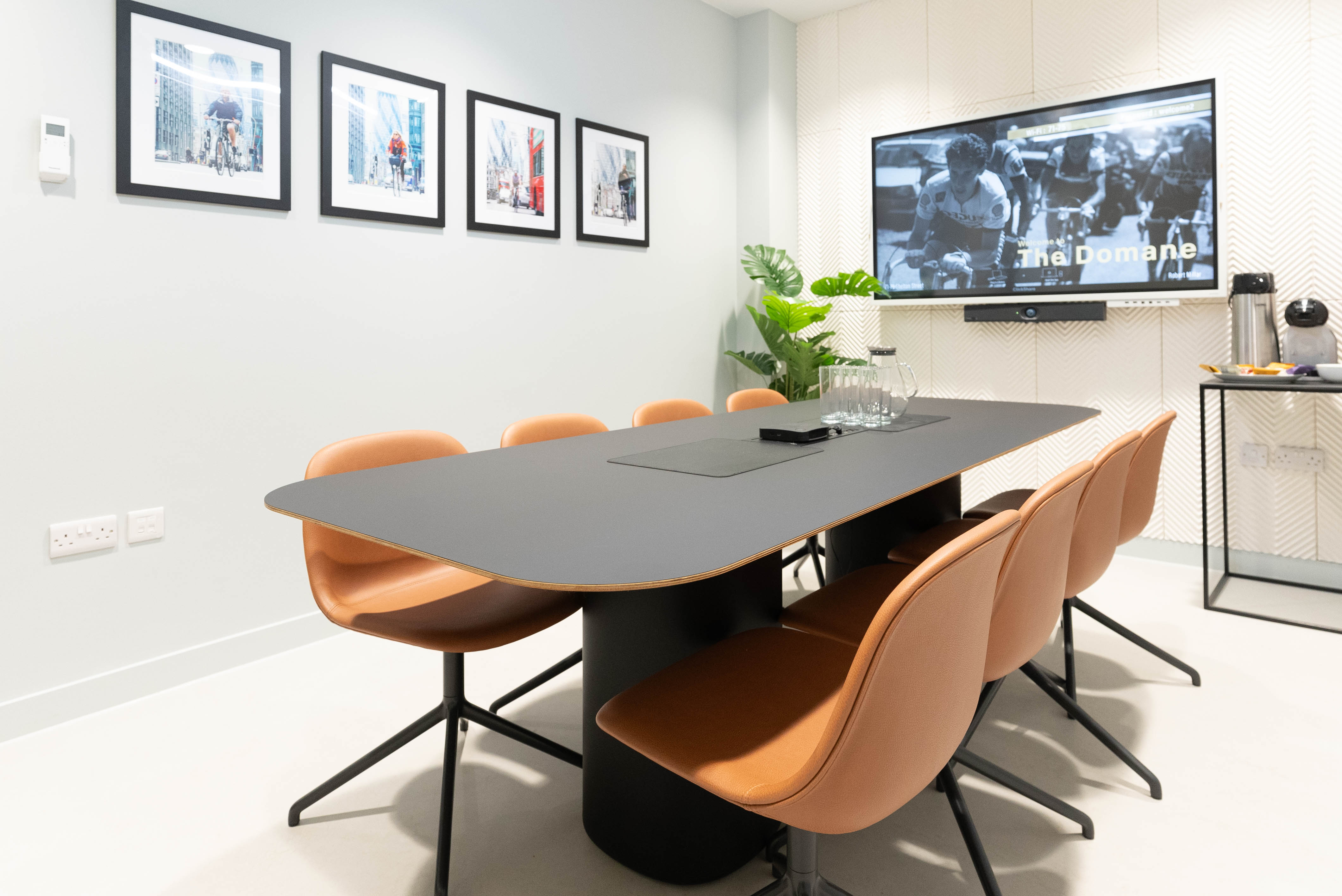 Modern meeting room with black table, orange chairs, ideal for collaboration and presentations. - Banner