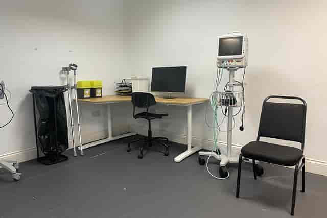 Minimalist medical consultation room with desk, computer, and equipment for events.