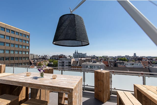 Stylish rooftop venue with wooden table, ideal for outdoor meetings and events.