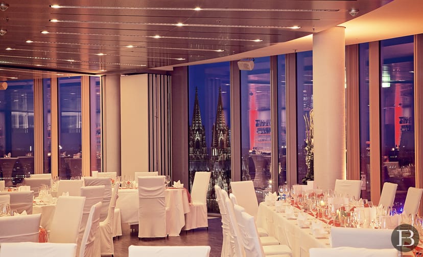 Elegant event space in Koelnsky with white table settings and city views for corporate gatherings.