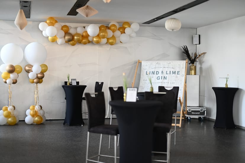 Stylish event space with black cocktail tables and gold balloon decor for networking events.