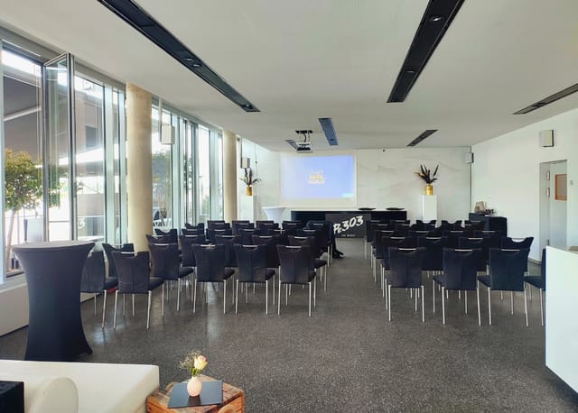 Modern event space with black chairs for corporate presentations in Pe303.