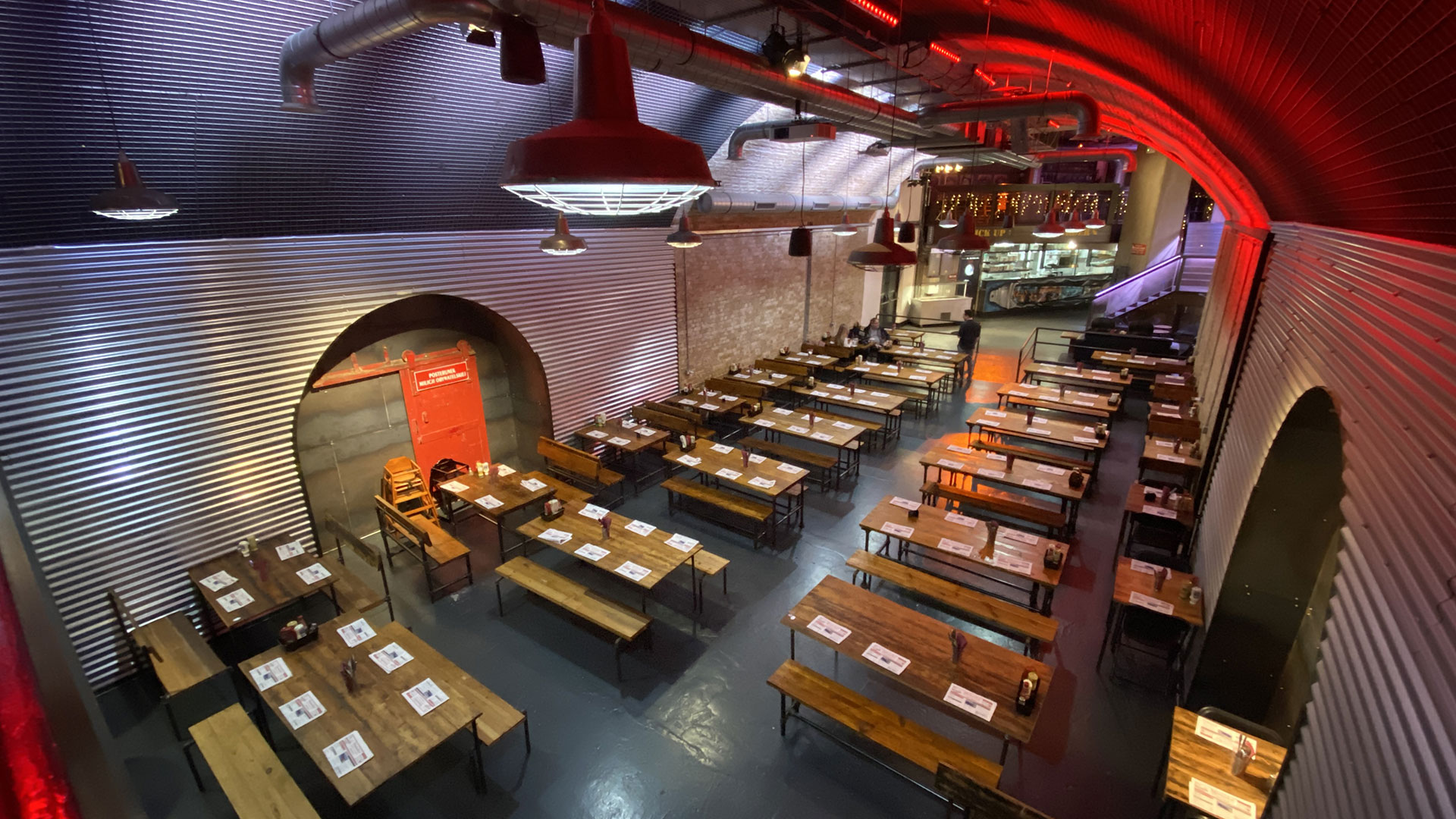 Spacious event venue with long wooden tables, ideal for conferences or workshops.