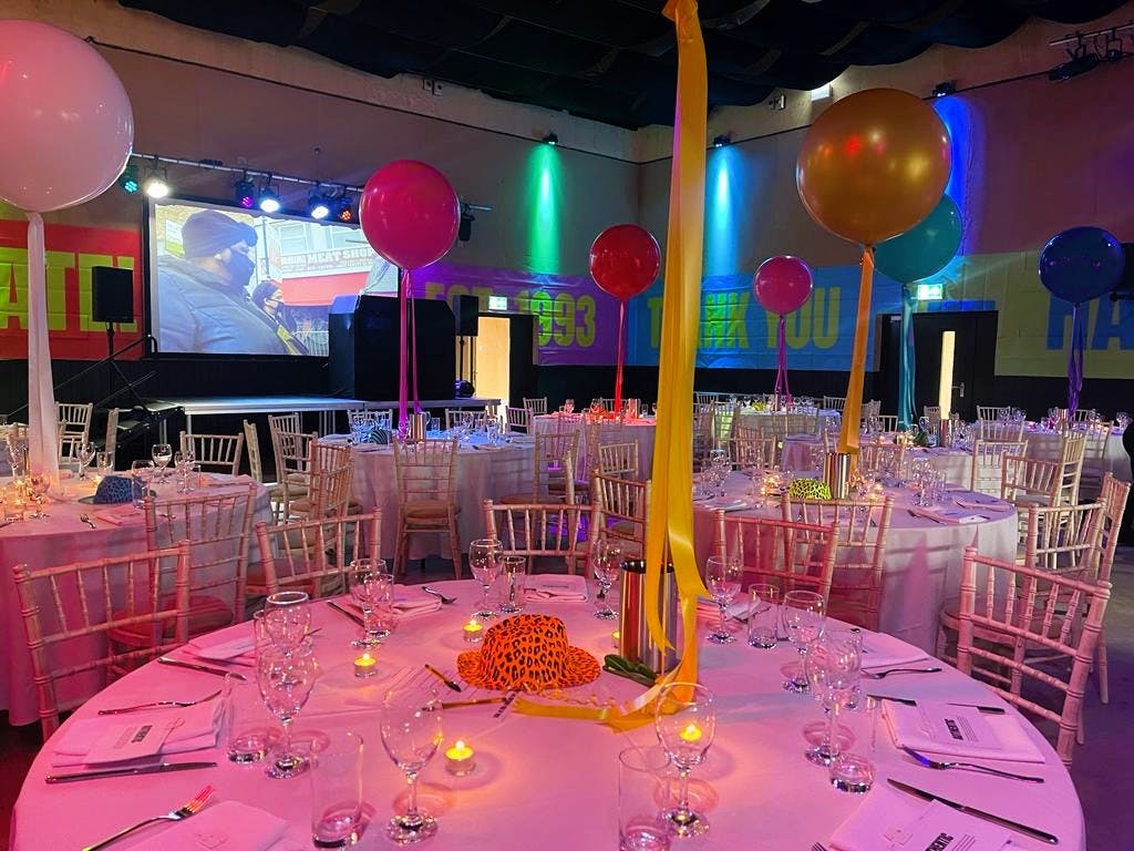 Vibrant event space in Hackney Bridge with elegant tables and colorful balloons for celebrations.