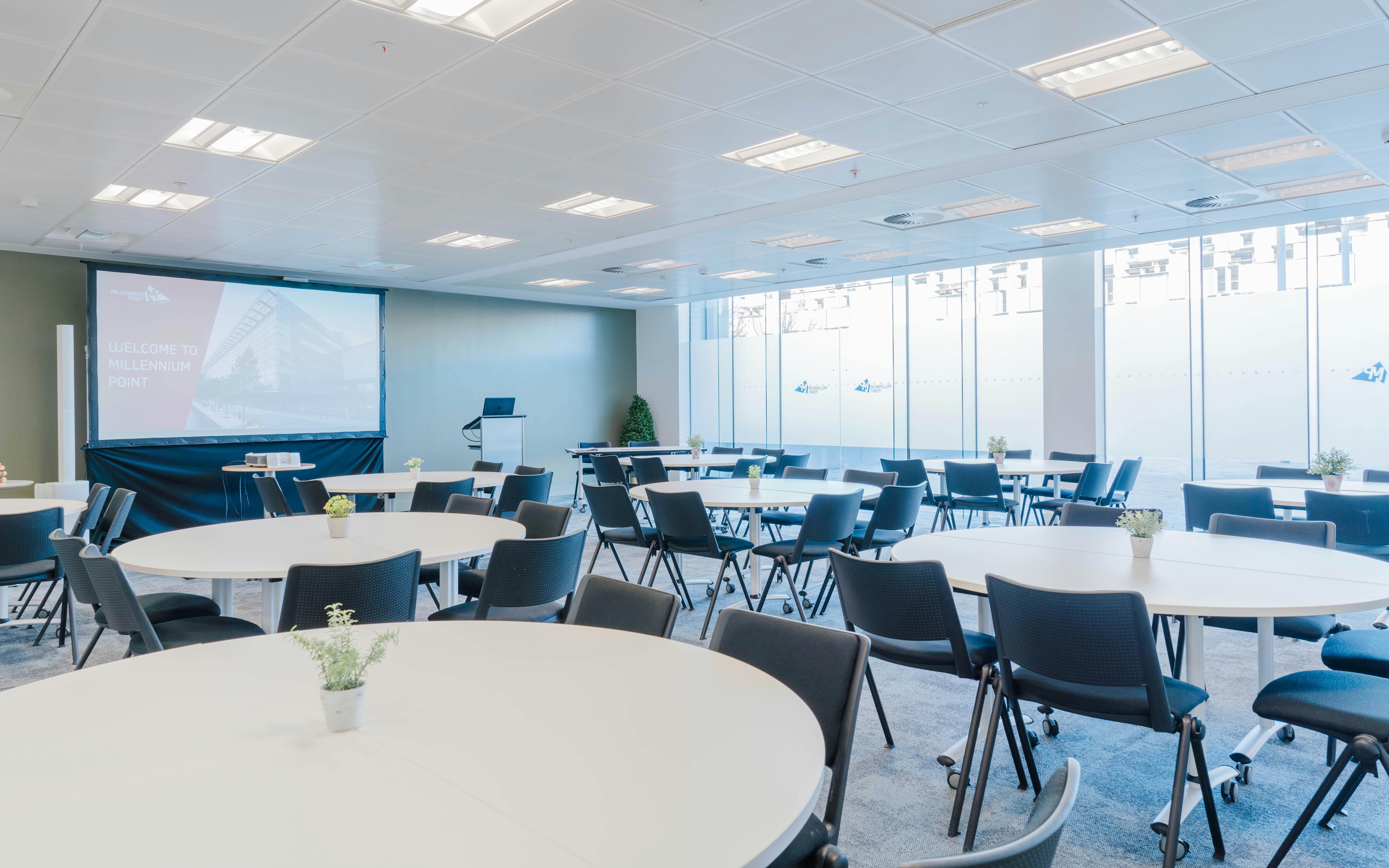 Versatile meeting space at Millennium Point with round tables and natural light for corporate events.