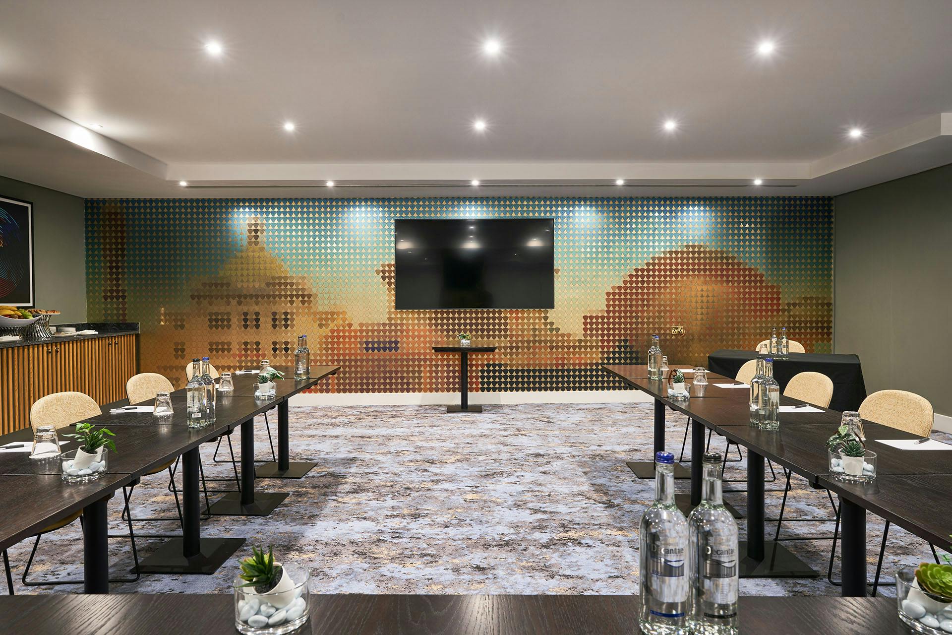 Modern meeting room at The Cumberland Hotel with dark wood tables and large screen.