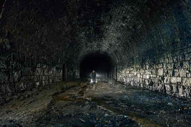 Disused railway tunnel with a person walking, ideal for unique event planning experiences.