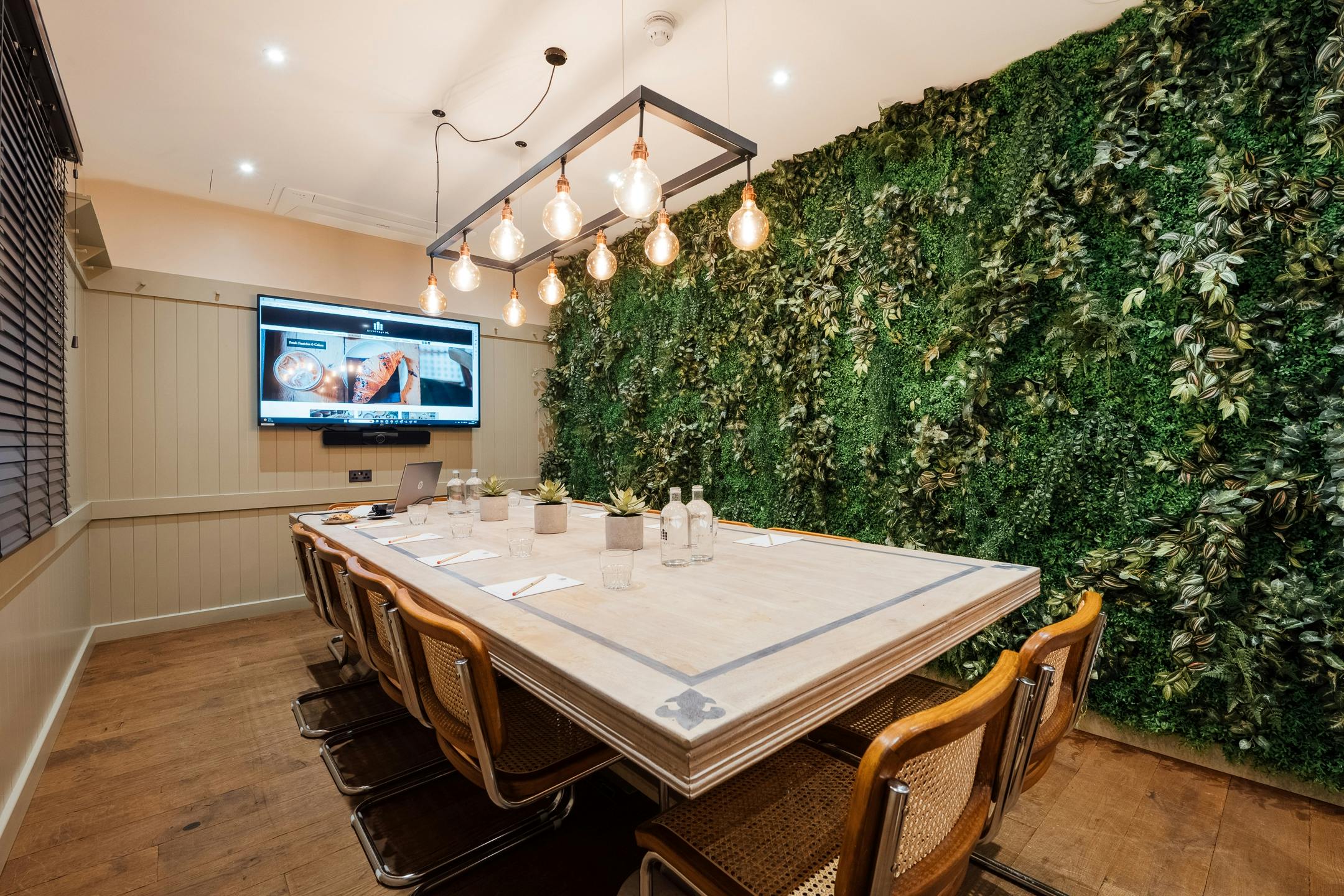 Modern meeting room with wooden table and green wall at Hermitage Rd Coffee & Bagel Bar.