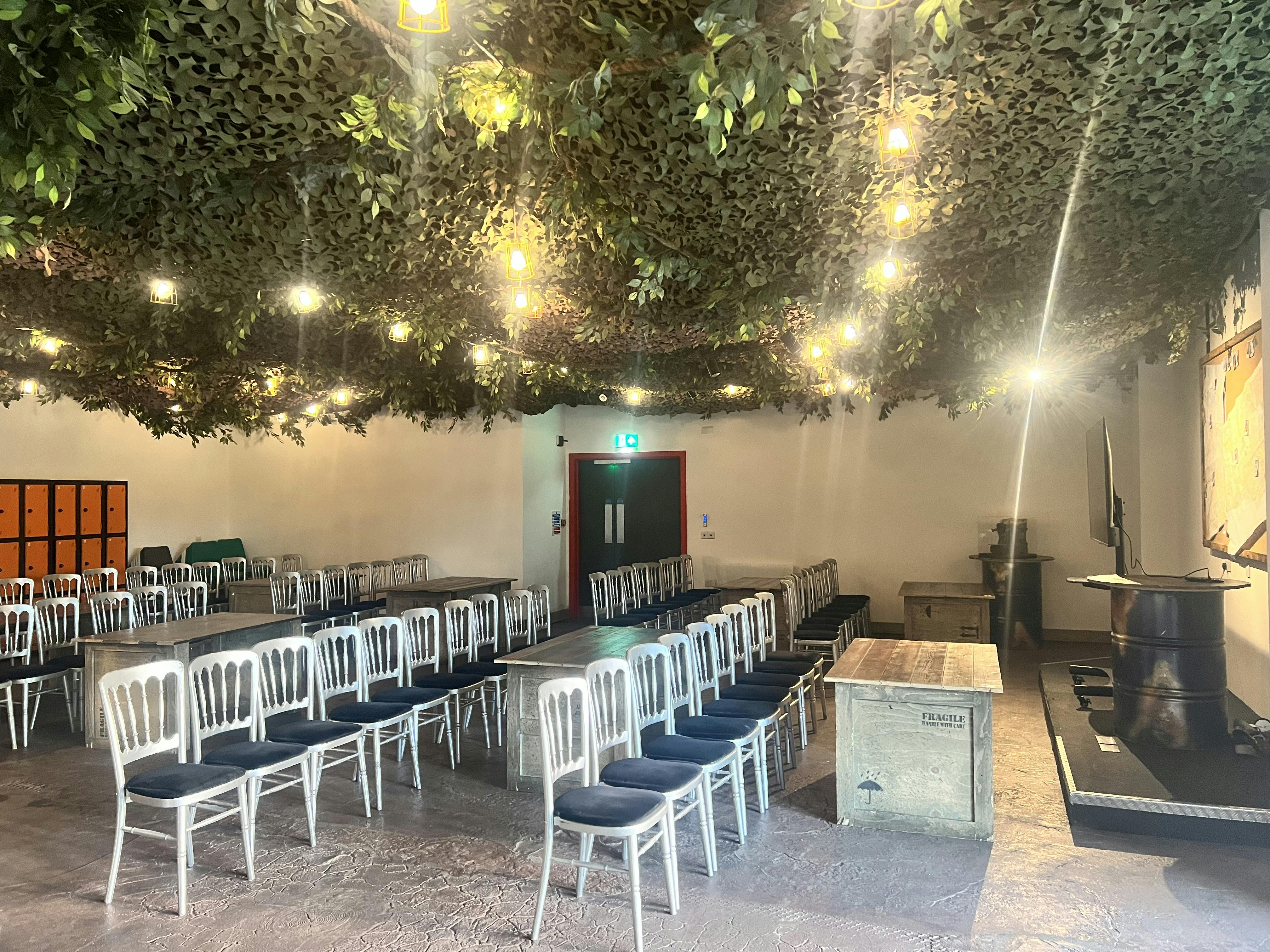 The Den at Bear Grylls Adventure: rustic meeting space with silver chairs, ideal for workshops.