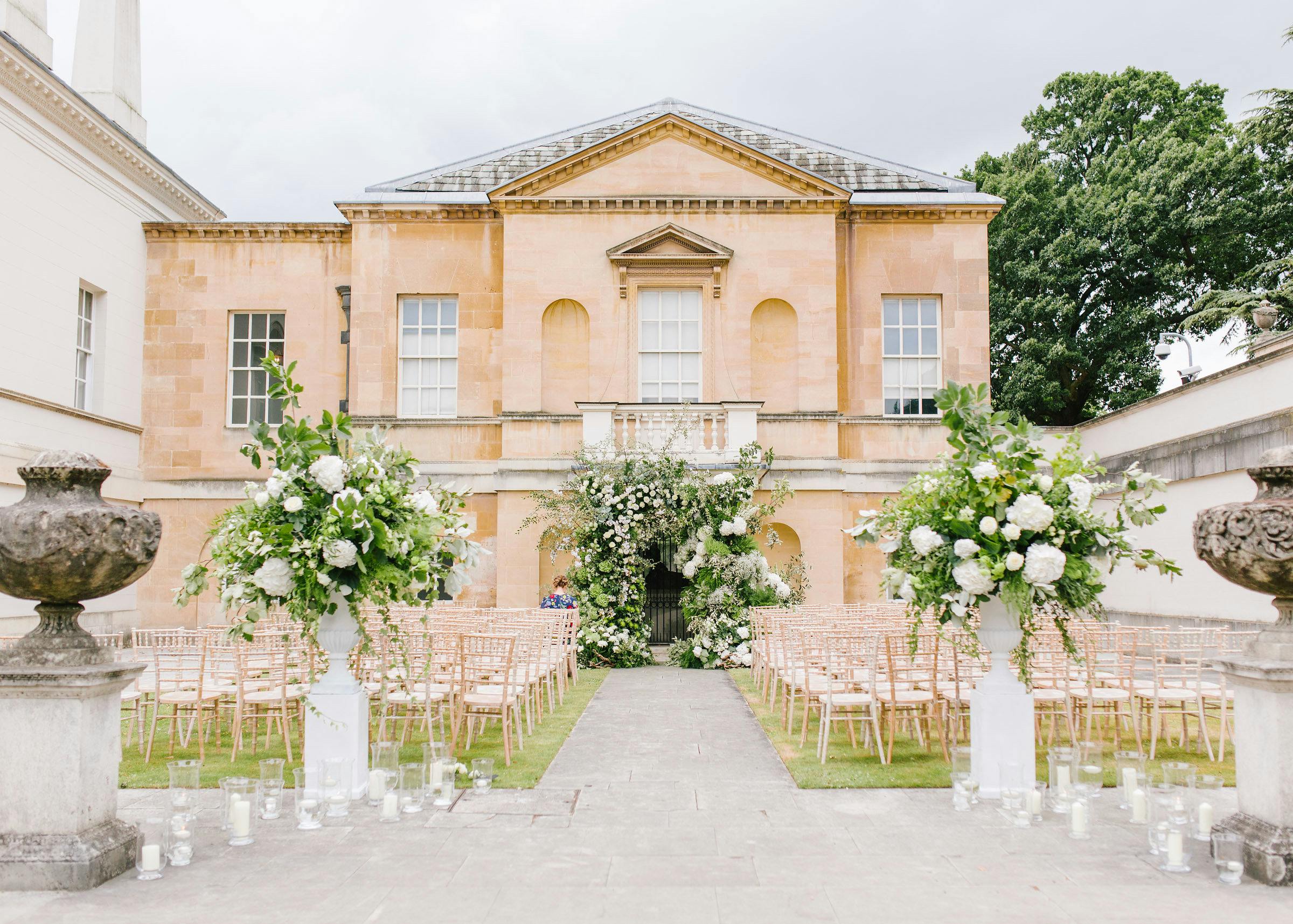 Outdoor wedding ceremony at Chiswick House with elegant floral arrangements and chiavari chairs.