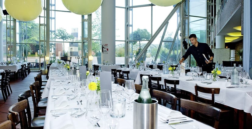 Elegant dining setup in Ludwig im Museum for events with floral centerpieces and natural light.
