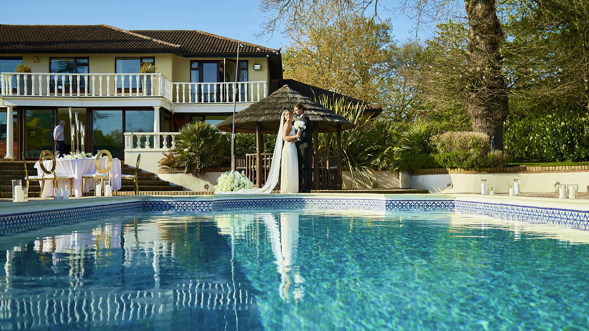 Elegant outdoor wedding venue with serene pool and lush greenery at The Villa Mansion.