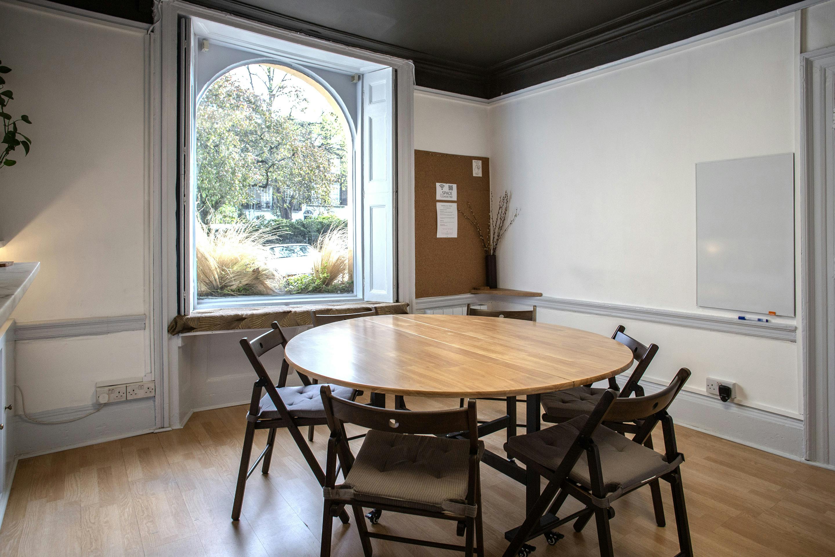 Well-lit meeting room with round table, ideal for collaborative discussions and presentations.