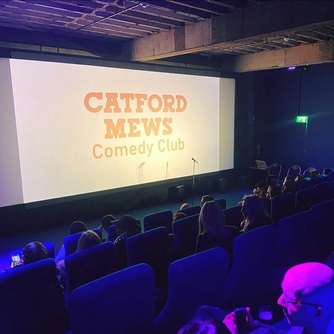 "Comedy club at Catford Mews with vibrant screens and spacious seating for events."