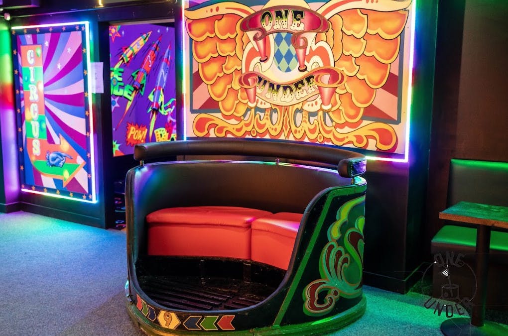 Vibrant seating area with neon lights for social gatherings in One Under Glasgow.