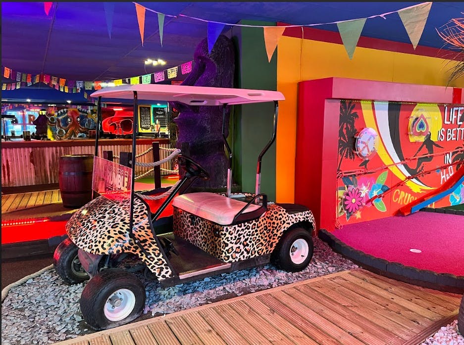 Vibrant Tahiti Course with leopard-print golf cart for team-building events in Putney.