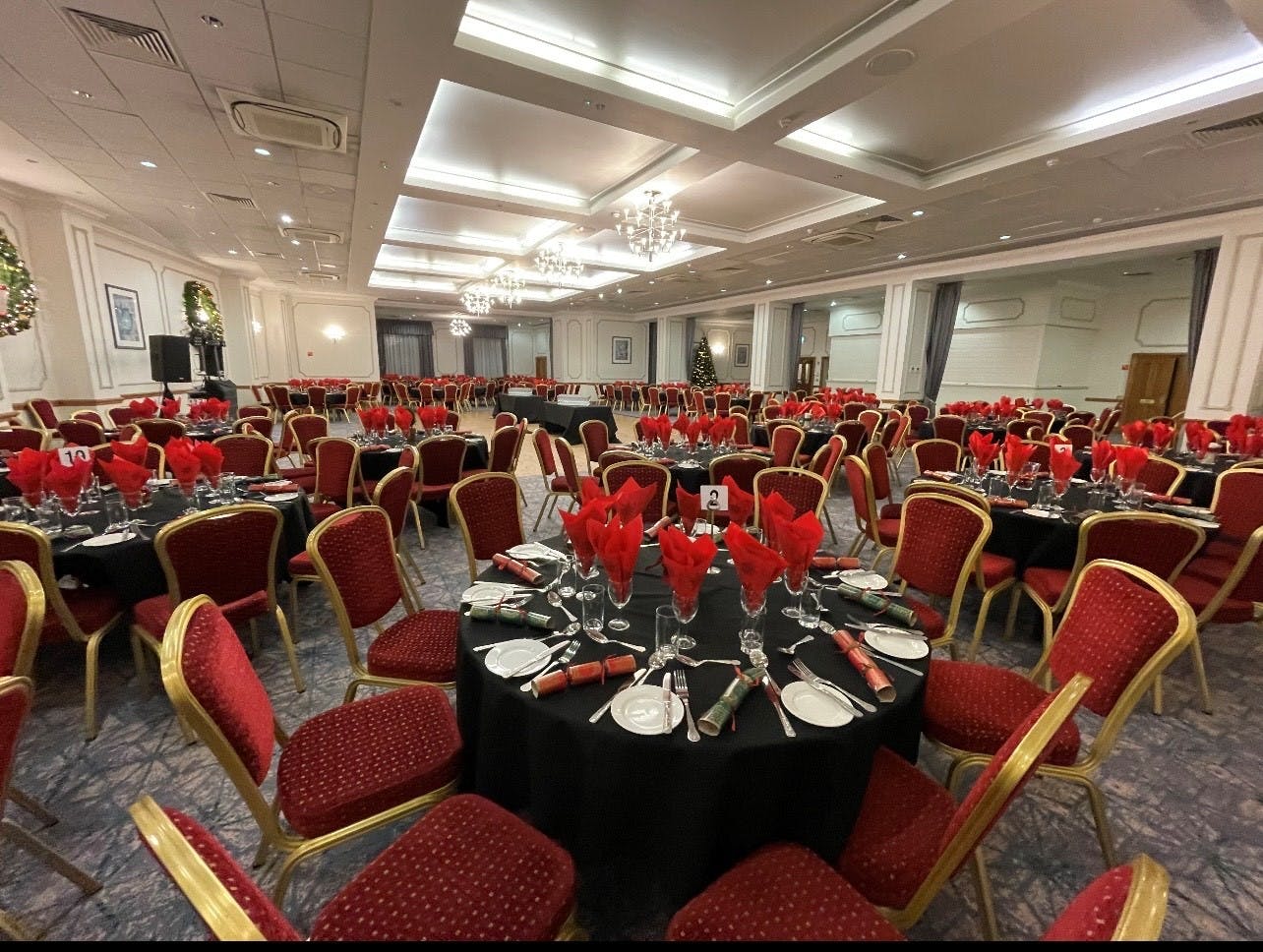 Wessex Suite banquet hall with elegant black tables and red napkins for weddings or corporate events.