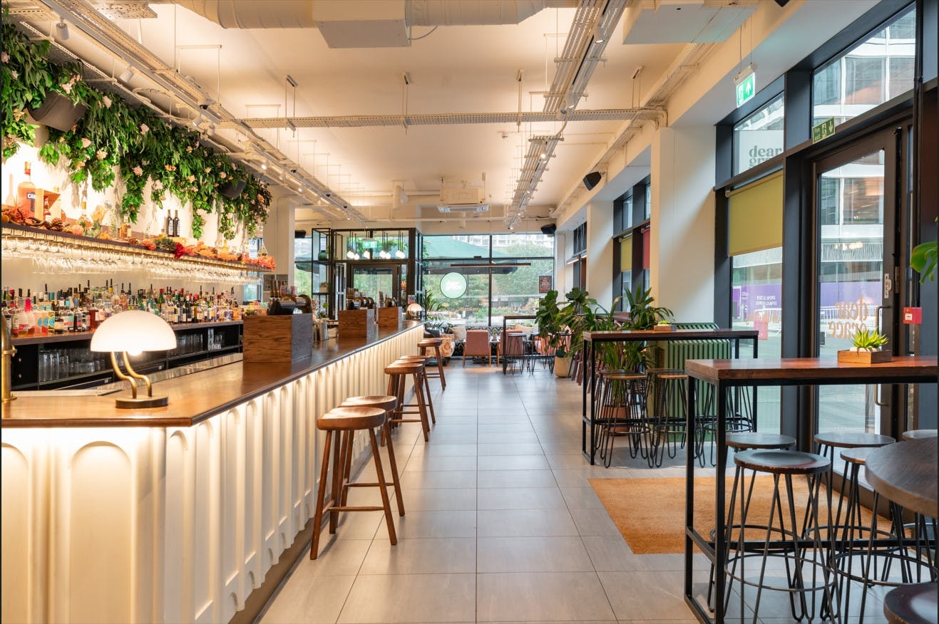 Modern event venue in Dear Grace with sleek bar and greenery for meetings and gatherings.