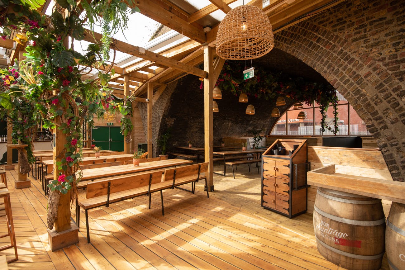 The Arches in Pergola Brixton: rustic event space with wooden benches for gatherings.