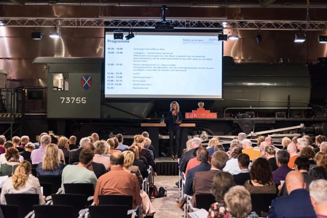 Expo at Spoorweg Museum with vintage train backdrop, engaging conference setting.