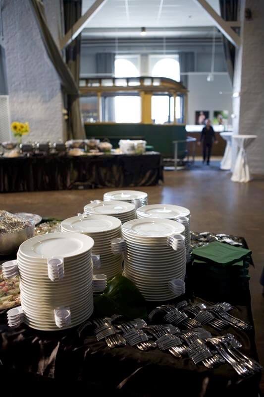 Tram Hall event space in Korjaamo Myynti, ready for a meal service with stacked plates.
