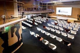Modern event space with white chairs for conferences at Espacio Bertelsmann.