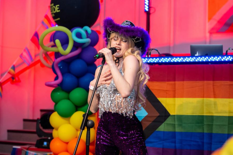 Vibrant performer at LGBTQ+ event in Dugdale Arts Centre with colorful backdrop. - Banner