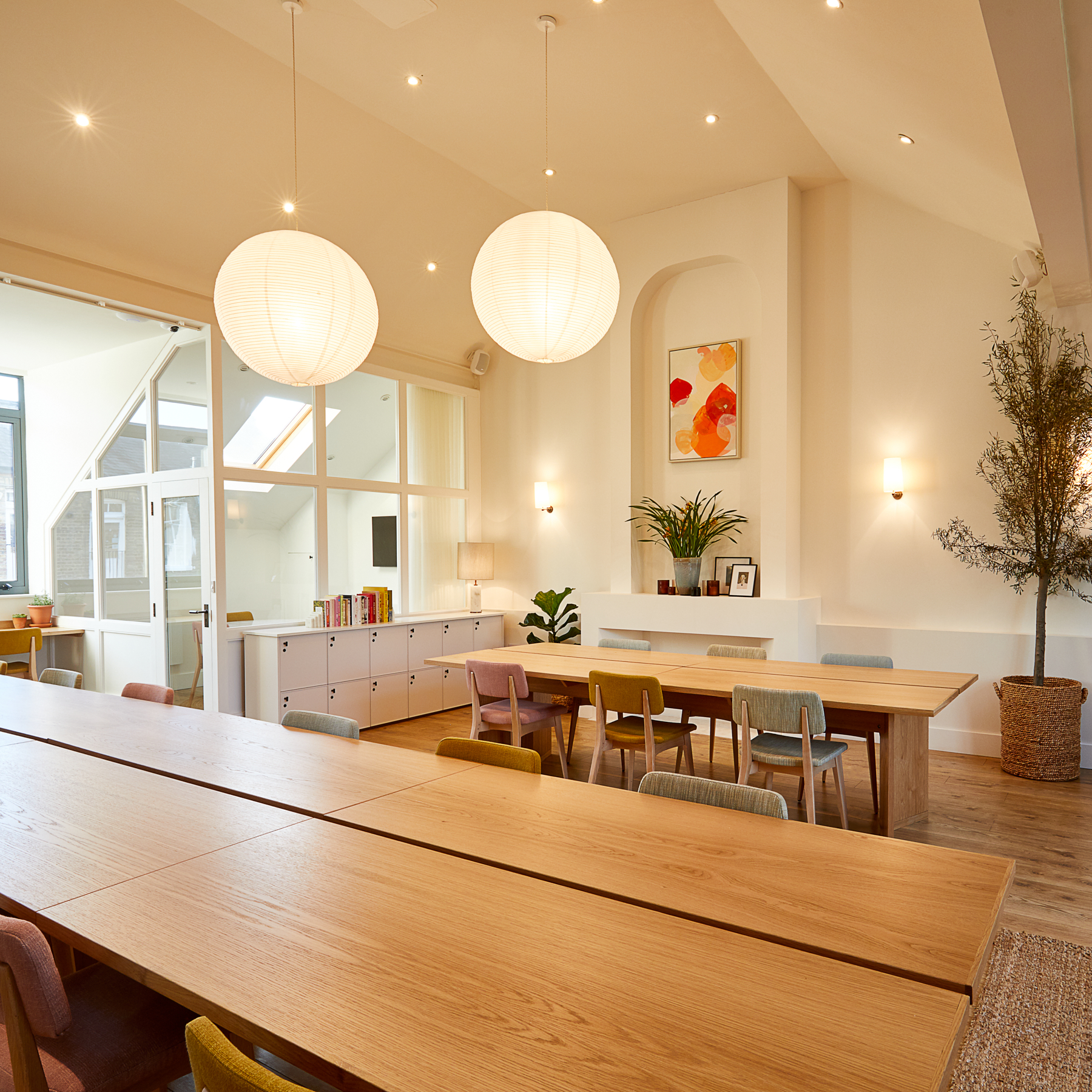 Bright meeting space with wooden table and colorful chairs, perfect for workshops. - Banner