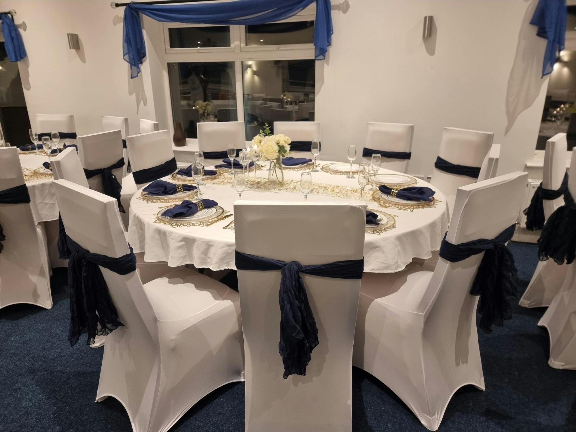 Elegant round table setup with navy blue sashes for weddings and upscale events.